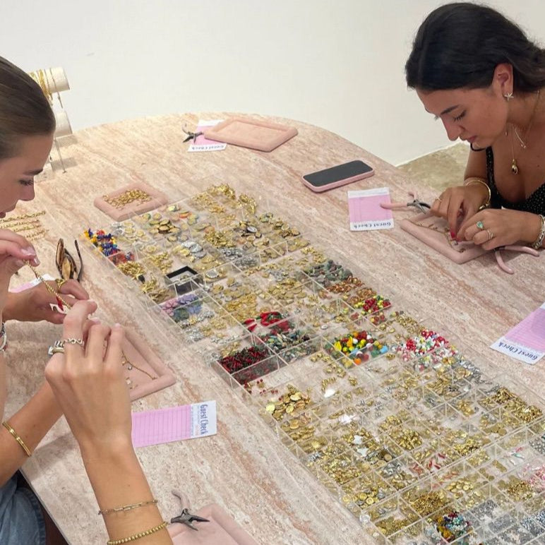Three women sitting around a table sorting through jewelry